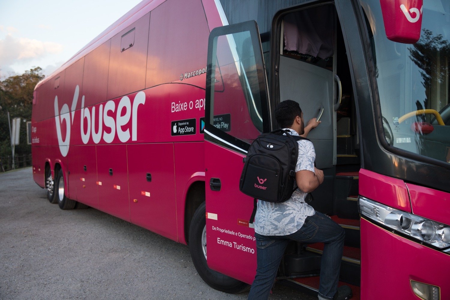 Homem embarcando em ônibus rosa da Buser