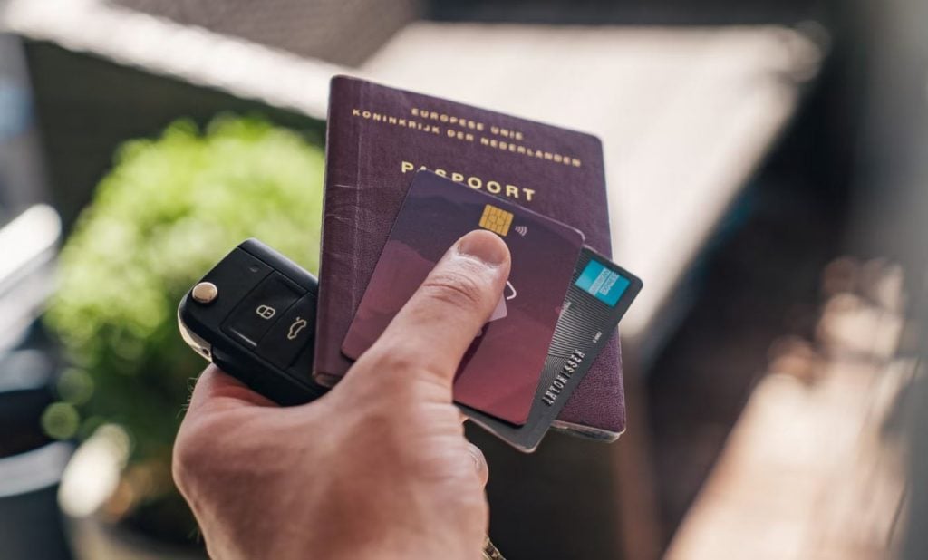 Mão segurando chaves, cartões e passaporte