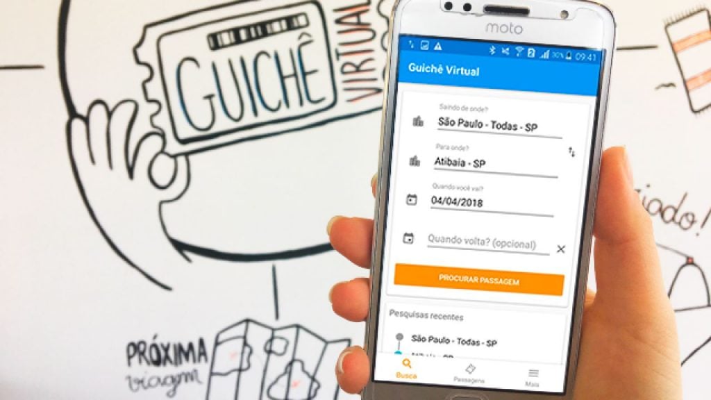Mão segurando celular app Guichê Virtual