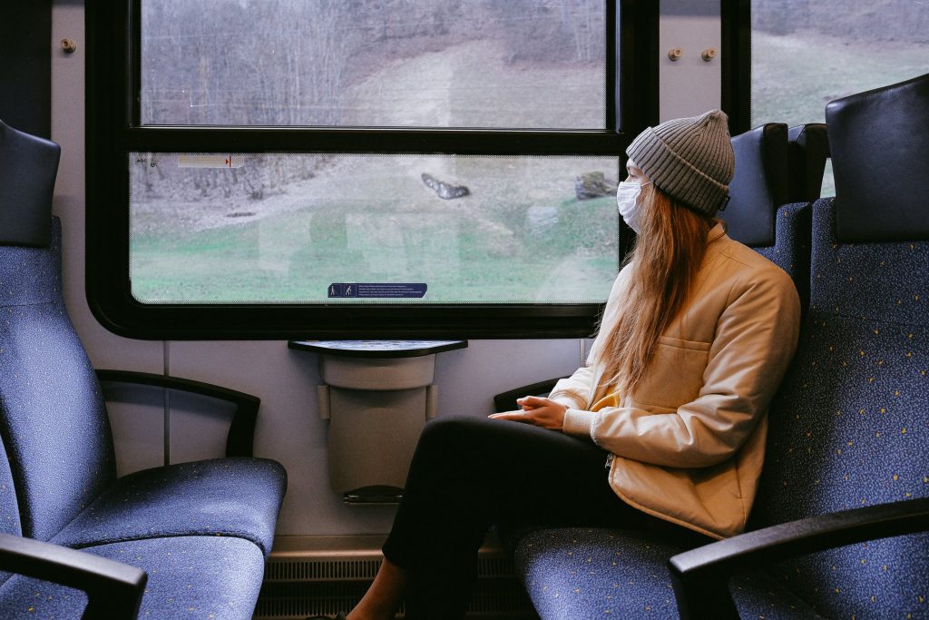 Mulher utilizando mascara sentada no banco da janela do trem
