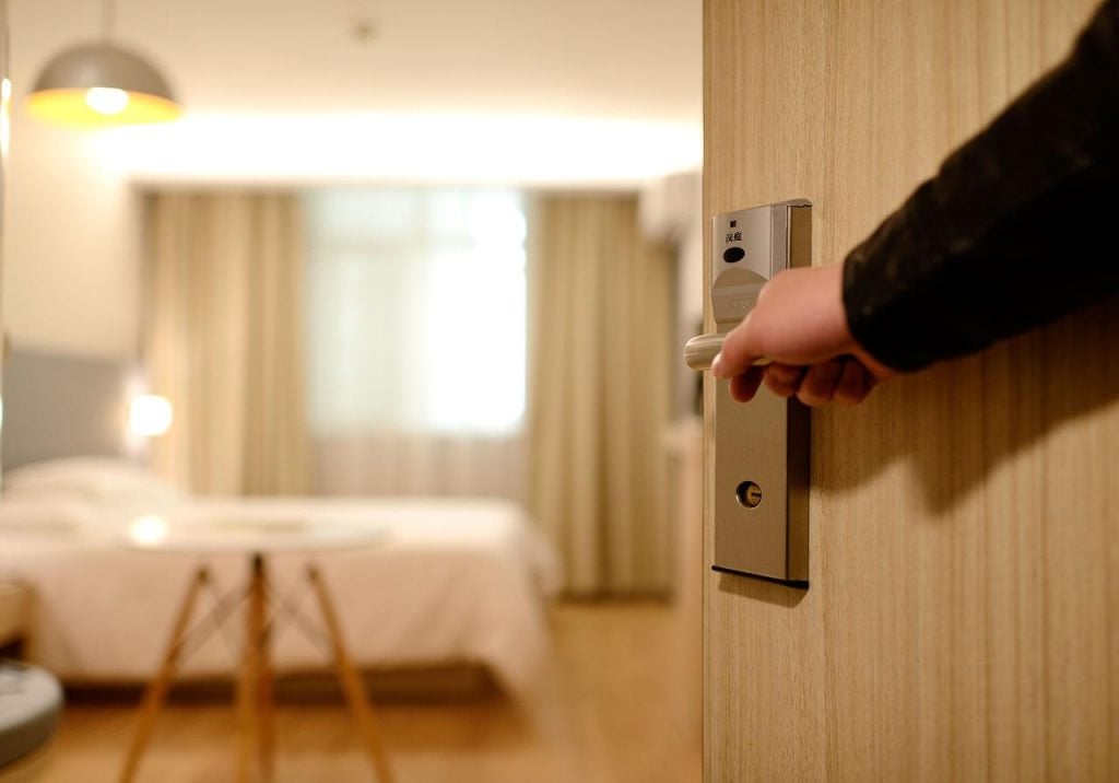 Mão abrindo porta de quarto de hotel