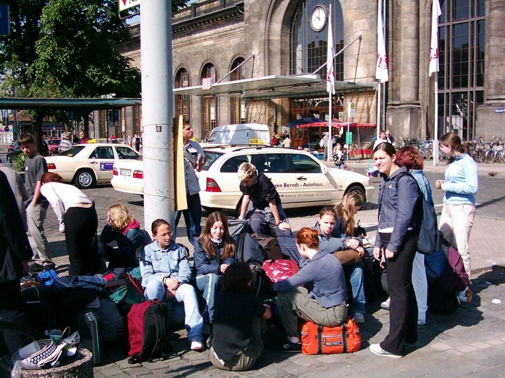 Adolescentes sentados na rua com malas