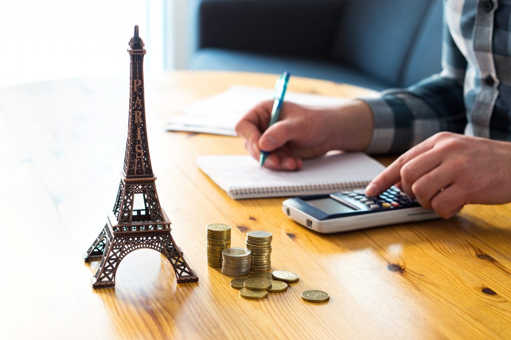 Pessoa calculando gastos com Torre Eiffel na mesa
