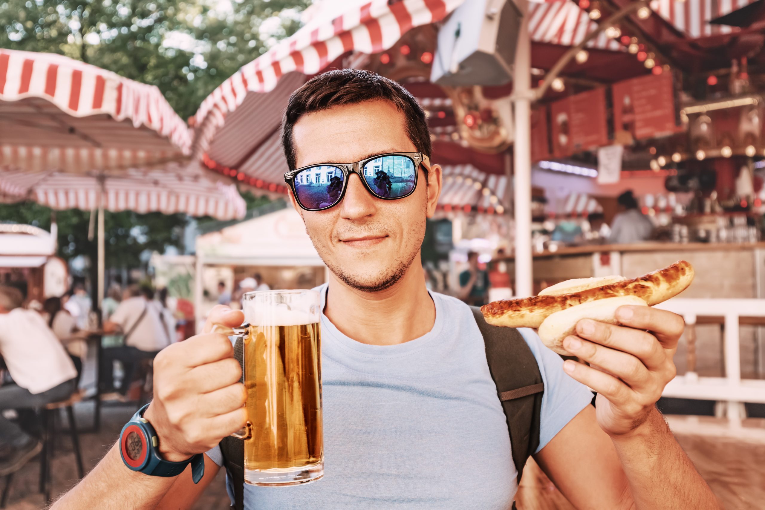 Homem segurando caneca de cerveja e hotdog