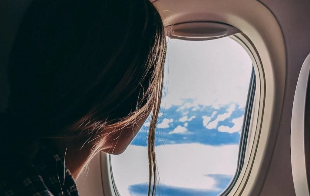 Mulher olhando pela janela de avião