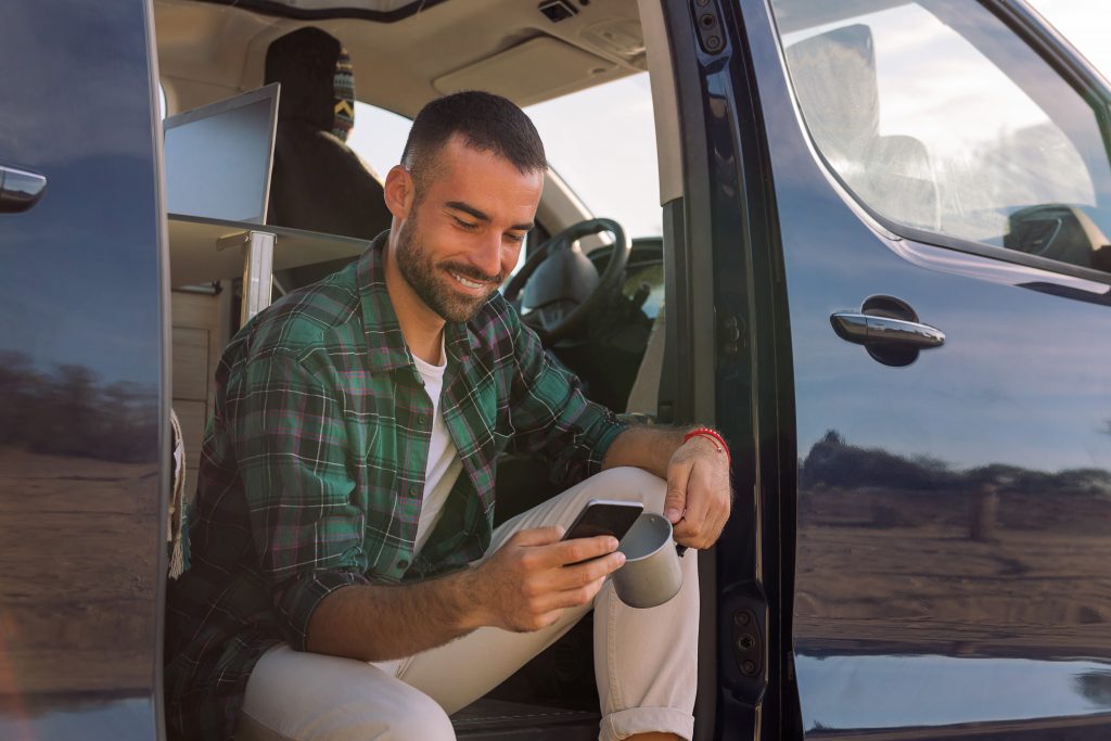 Homem usando celular em van