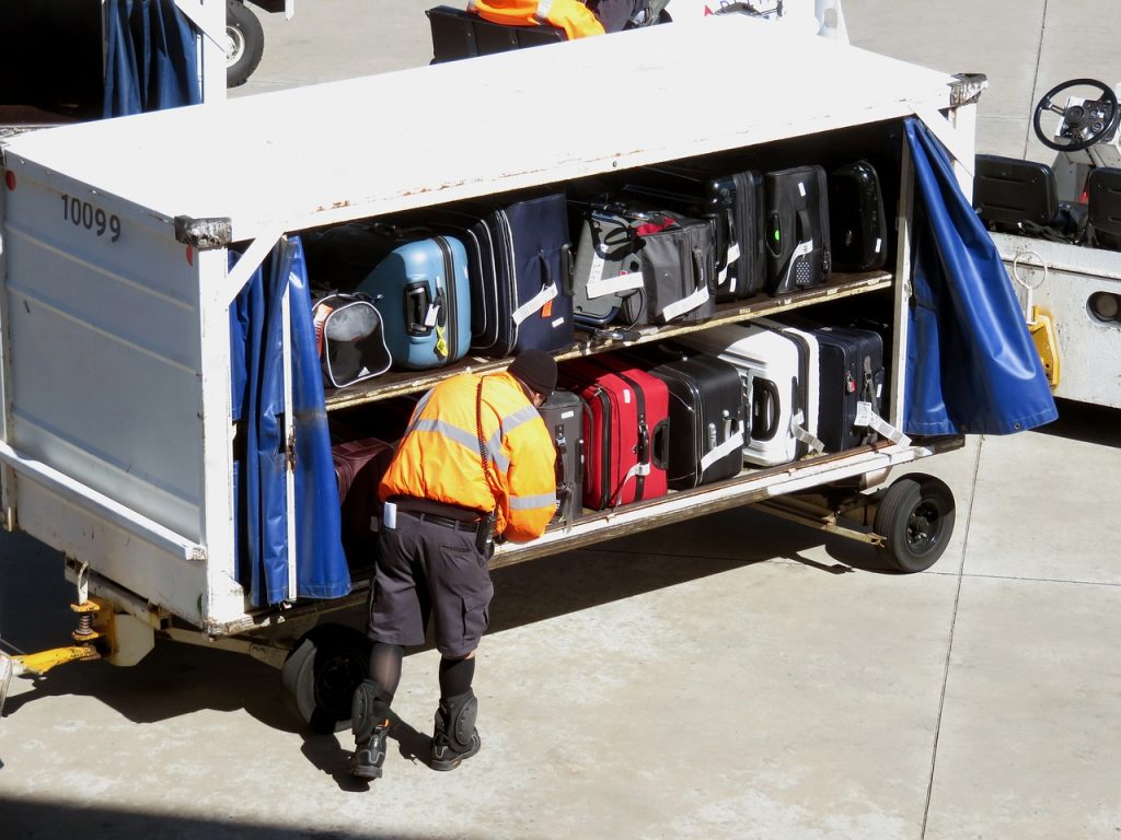 Funcionário de aeroporto carregando avião com malas